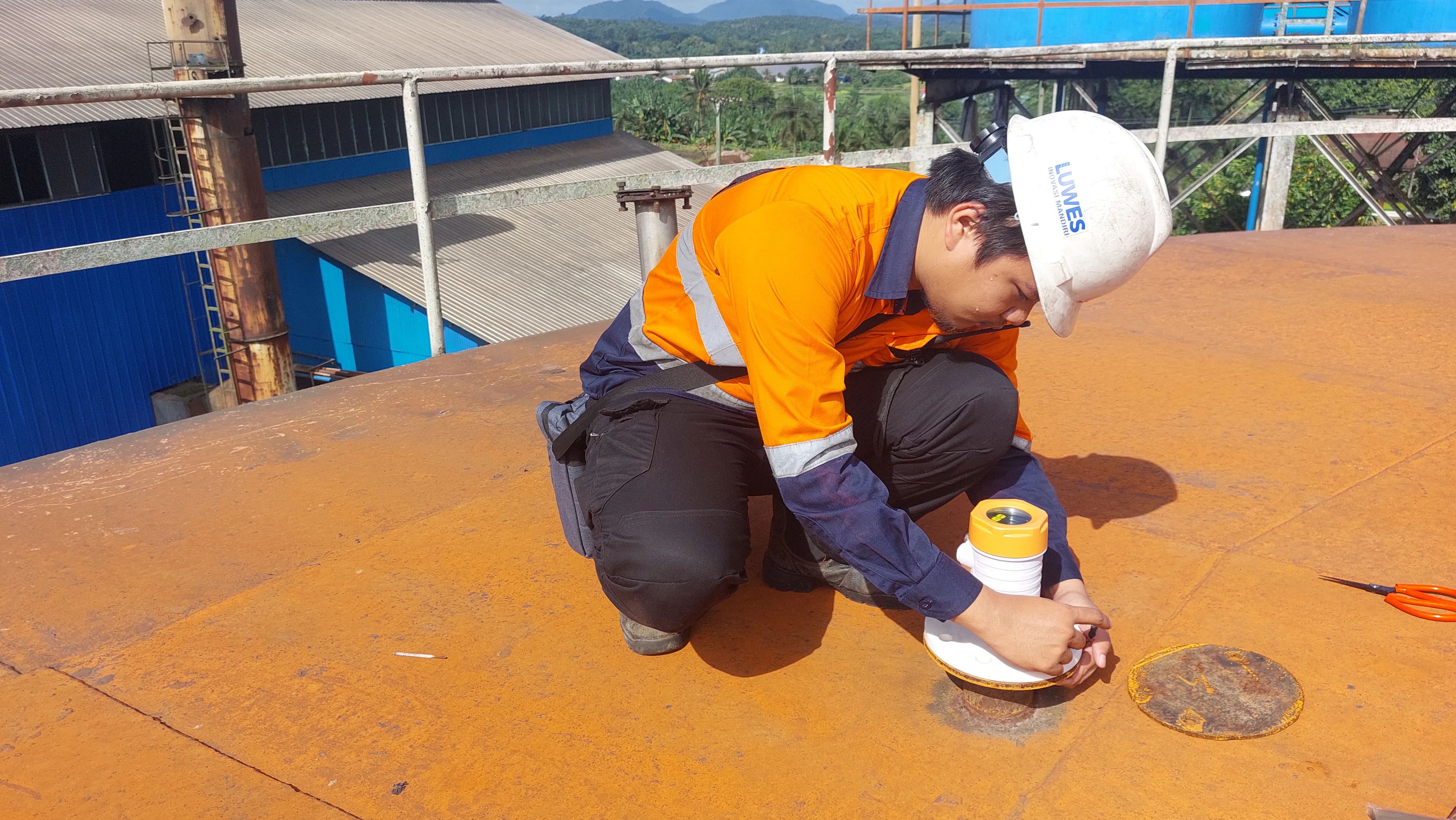 Technician fitting a radar sensor on a storage tank